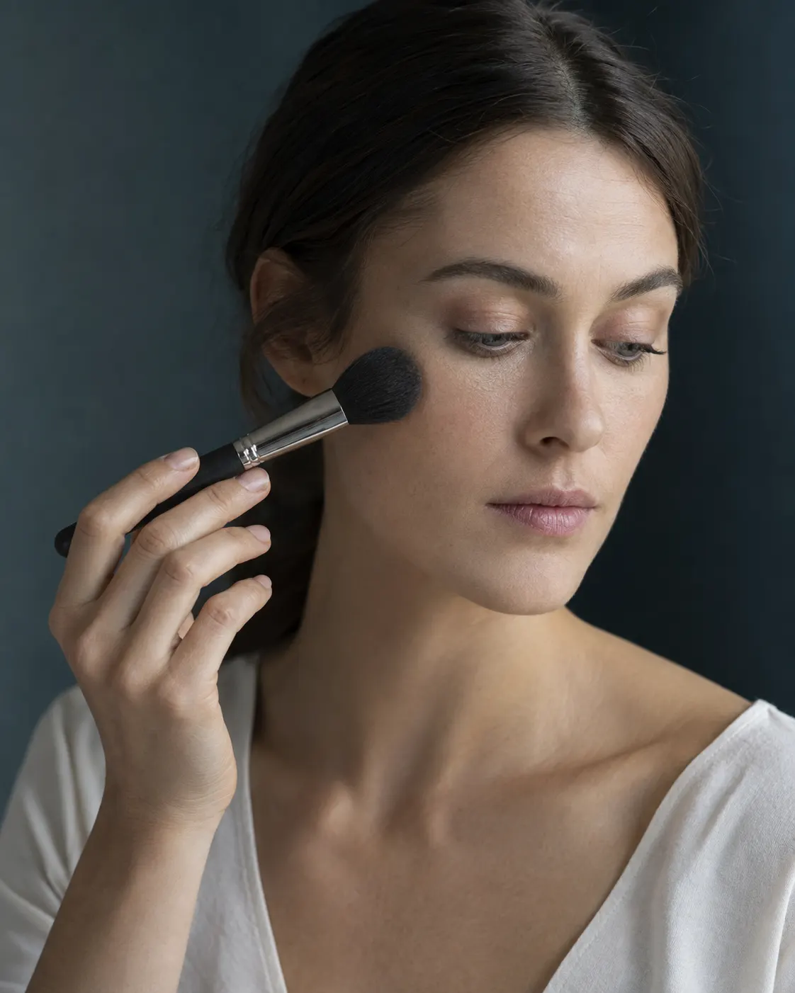 KI-generierte Editorialszene mit Make-up-Pinsel nahe einer Wange
